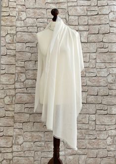 Our ivory bridal shawl is the perfect accessory for your special day. A lightweight beach wedding pashmina shawl that offers elegance and comfort is ideal for summer brides. This raw edge stole features a simple yet sophisticated design, adding a touch of refinement to your ensemble. With this ivory wedding wrap, you can wrap it around your arms or drape it over your shoulders. Your allure will be beautifully enhanced with this bridal pashmina scarf, whether you are walking down the aisle or cel White Pashmina Shawl With Traditional Drape, White Pashmina Shawl In Traditional Drape, Elegant Cream Pashmina Shawl In Traditional Drape, White Pashmina Dupatta Shawl, Pashmina Shawl For Wedding In Traditional Drape, Wedding Pashmina Shawl In Traditional Style, Wedding Pashmina Shawl In Traditional Drape, Cream Pashmina Dupatta For Wedding, Cream Pashmina Scarves For Wedding