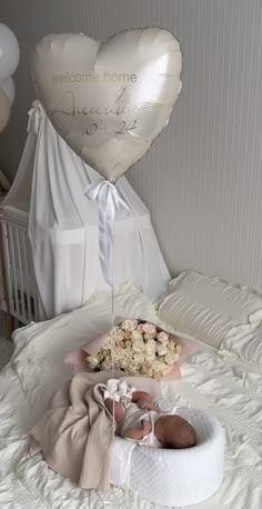 a baby in a crib next to a heart shaped balloon