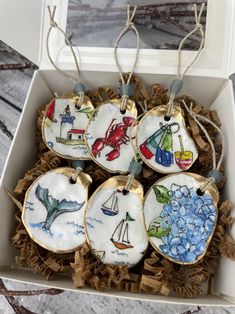 four decorated cookies in a box with string hanging from the top and on each ornament