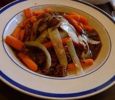 a white plate topped with meat and veggies on top of a wooden table