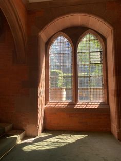 an arched window in a brick building with sunlight streaming through the windows and casting shadows on the wall