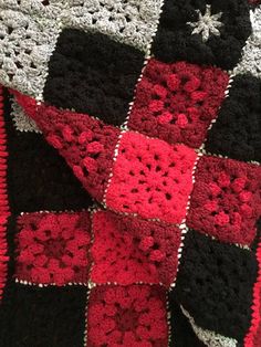 a crocheted blanket is laying on top of a bed with red and black squares