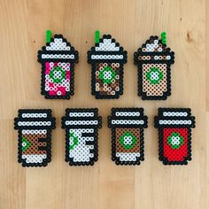 six perler bead coasters are arranged on a wooden surface, each with different designs and colors