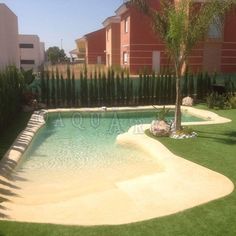 an empty swimming pool in the middle of a lawn area with palm trees and grass