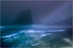 the ocean is very dark and blue with light coming from it's headlight