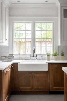 a kitchen with wooden cabinets and white counter tops, along with a large window over the sink