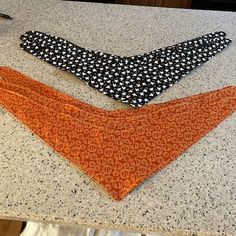 two ties sitting on top of a counter next to a pair of scissors and an orange bandana