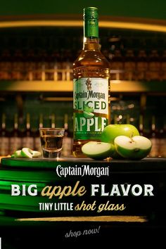 a bottle of apple flavored liquor sitting on top of a green tray with apples