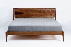 a bed with a wooden headboard and foot board on top of it, against a white background