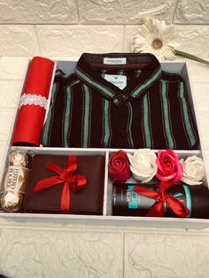 an open box with some items in it and a flower on the table next to it