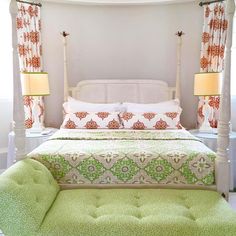 a white bed with green and red bedspread, pillows and two lamps on either side