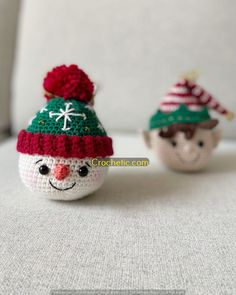 two small crocheted snowmen sitting on top of a white couch next to each other