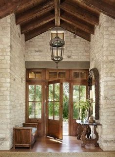 an entry way with wooden doors and brick walls, surrounded by stone pillars that lead into the living room