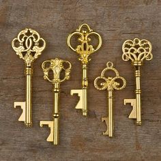 five antique keys are lined up on a wooden surface