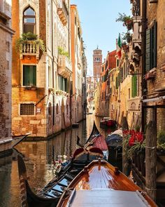 a boat is traveling down a narrow canal in venice, italy on a sunny day