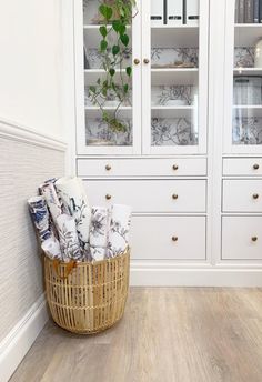 a wicker basket sitting in front of a white china cabinet