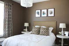 a white bed topped with pillows next to two lamps and pictures on the wall above it