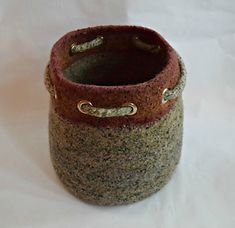 a close up of a small pot on a white surface with some gold chains around it