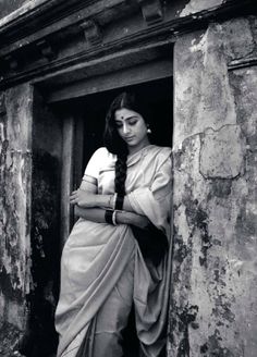 black and white photograph of a woman in sari leaning out the window with her arms crossed