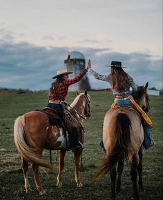 two women are riding horses in a field and one is giving the finger to another woman