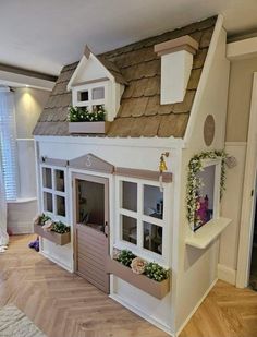 a doll house made out of cardboard with windows and flowers on the roof, sitting in a living room