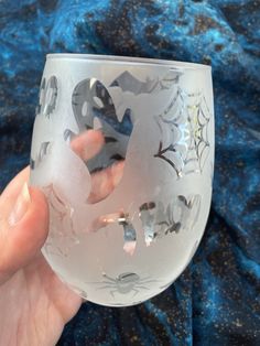 a hand holding a wine glass with designs on it