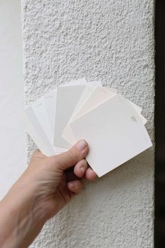 a hand holding some white cards against a wall