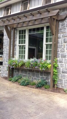 a brick house with white windows and flowers in the window boxes on the front porch