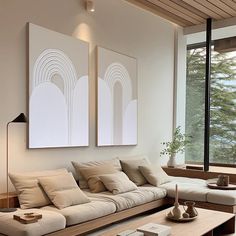 a living room filled with furniture next to a large window and a painting on the wall