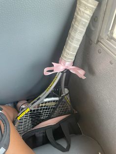 a tennis racket is tied to the back of a car with a pink bow