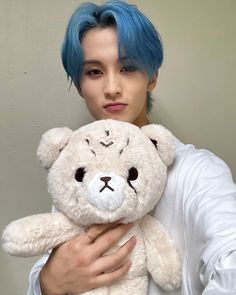 a man with blue hair holding a white teddy bear