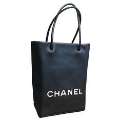 This stylish Chanel mini shopper tote bag is crafted of calfskin leather in black with letters CHANEL in white fabric sewn on the front. Karl Lagerfeld once admitted to collecting chic paper bags which made him decide to immortalize the iconic paper shopper bags. These Chanel shopper totes were also featured on Chanel Spring/Summer Runway in 2009. This mini tote features rolled leather handles that open to an interior lined with black and white jacquard embroidered with Chanel’s iconic symbols. High-end Shoulder Bag With Logo For Everyday Use, High-end Shoulder Bag With Logo, High-end Everyday Shoulder Bag With Logo, Designer Shopping Bags With Logo, High-end Logo Shoulder Bag For Everyday Use, High-end Black Shopping Bags, Logo Tote Bag For Shopping, Modern Shoulder Bag With Logo For Shopping, Classic Black Bag With Logo