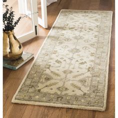 a large rug on the floor in front of a white door and vase with flowers