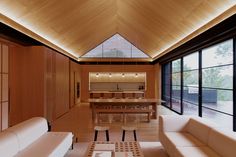 a living room filled with furniture next to large windows and wooden ceilinging on the walls