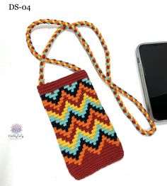 a cell phone is laying next to a crocheted bag on a white surface