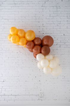 several balloons are arranged on a white brick wall