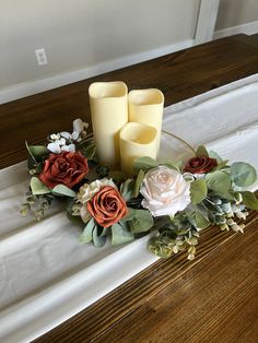 three candles are sitting on a table with flowers