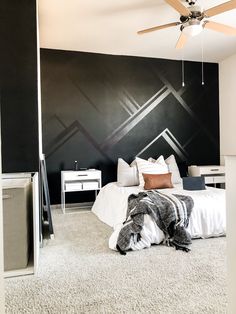 a bedroom with black and white walls, carpeted flooring and a ceiling fan