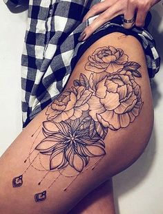 a woman is showing off her thigh with flowers on the side and tattoos on it