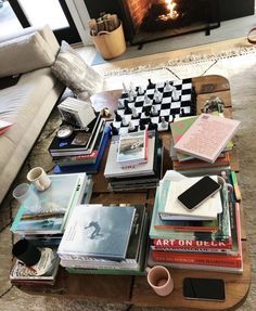 a coffee table filled with books next to a fire place