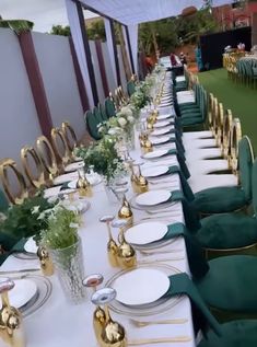 a long table is set with green velvet chairs and white plates, gold trimmings