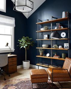 a living room with blue walls and leather chairs in front of a book shelf filled with books