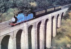 a blue and black train traveling over a bridge