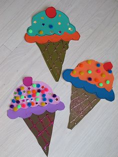 three ice cream cones decorated with sprinkles and polka dots on white wood