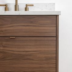 a bathroom vanity with marble top and two faucets