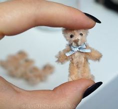 a person holding a tiny teddy bear in their hand