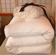 a pile of white pillows and blankets on a bed