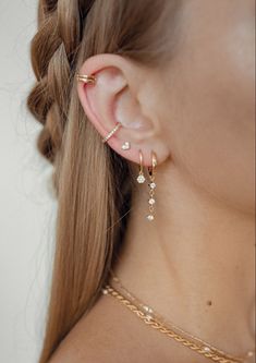 a close up of a woman's ear wearing gold jewelry