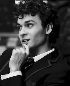 black and white photograph of a young man with curly hair wearing a suit looking to the side