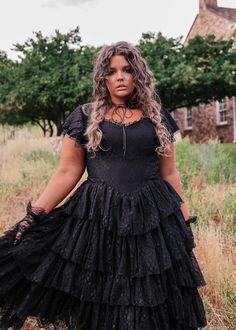 a woman standing in a field wearing a black dress